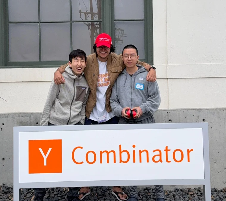 Tario You, Dylan Pak, and Ojas Kandhare standing behind a Y Combinator sign